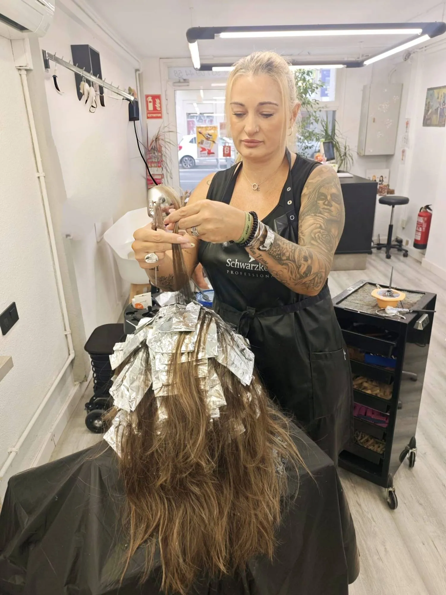 Estilista aplicando mechas con papel de aluminio en el salón